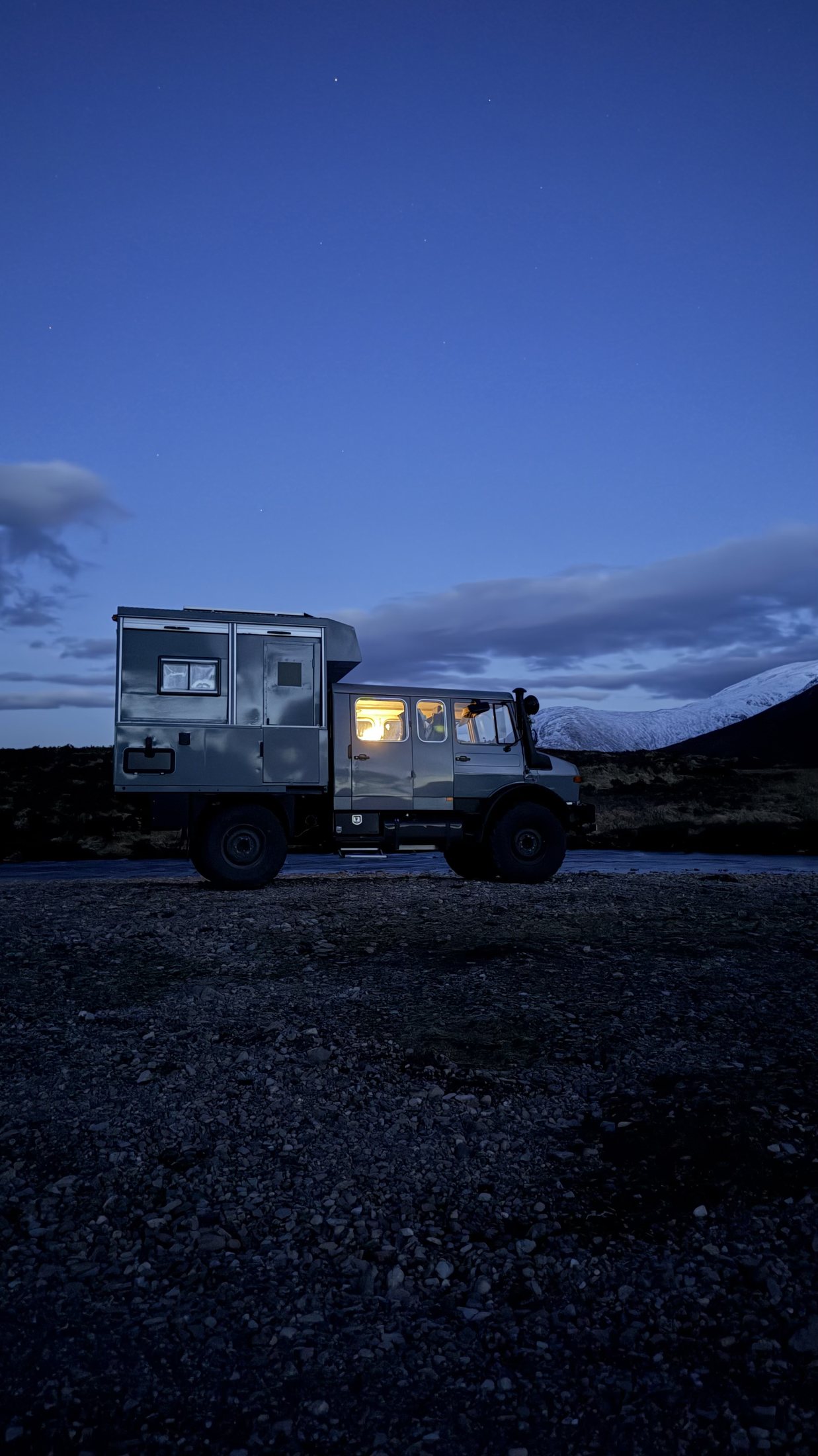 Der CTO Unimog in der blauen Stunde vor schneebedeckten Bergen